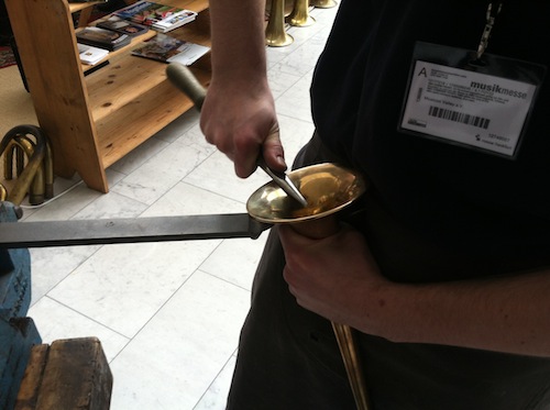 A German horn maker repairs a trumpet.