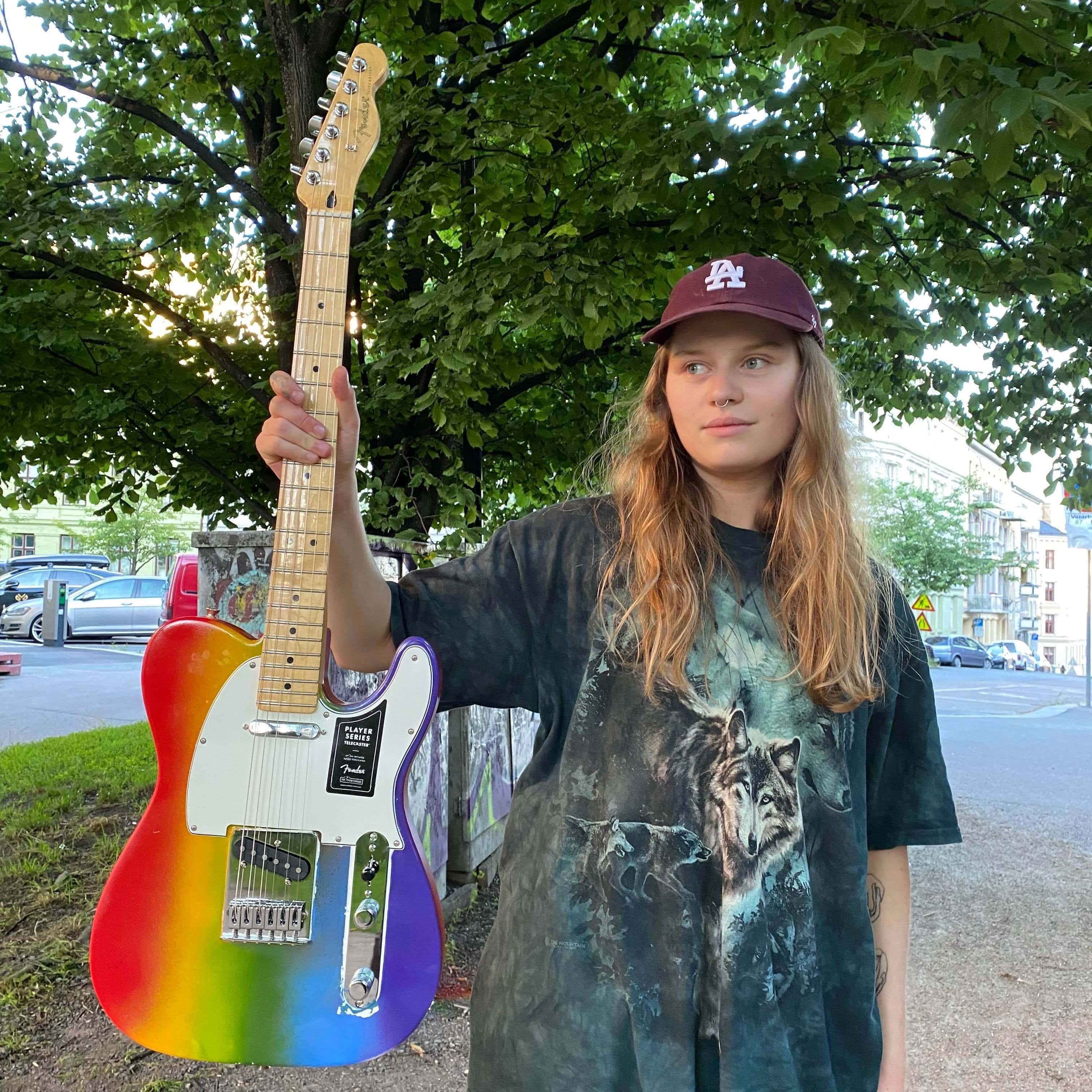 Pop Songwriter girl in red Designs A One-of-a-kind Rainbow Fender To Raise Money For Kaleidoscope Trust In Support Of The Global LGBTQ+ Community
