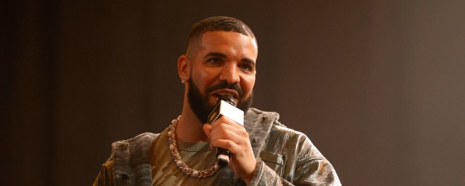 Drake pictured speaking into a microphone onstage at a rap battle.
