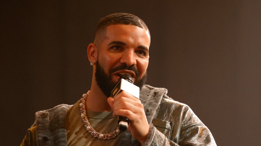 Drake pictured speaking into a microphone onstage at a rap battle.
