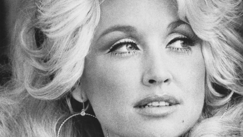 A young Dolly Parton is pictured looking into the distance.