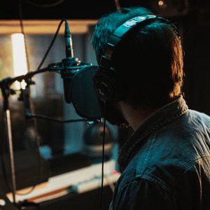 Male singer singing into a recording studio microphone.
