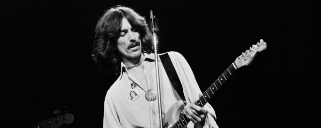 George Harrison plays the guitar on stage in 1974.