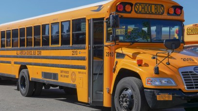 A yellow school bus is pictured in a parking lot, like the ones that children sing about in "Wheels on the Bus."