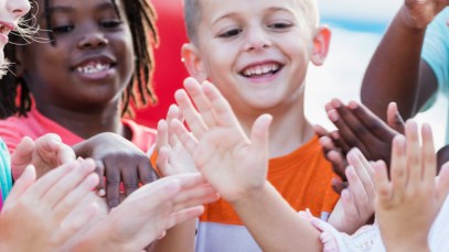 A group of children are seen playing and singing the "Miss Mary Mack" rhyming game.