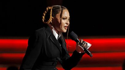 Madonna, dressed in a black suit, speaks into a microphone at the 2023 GRAMMY Awards.