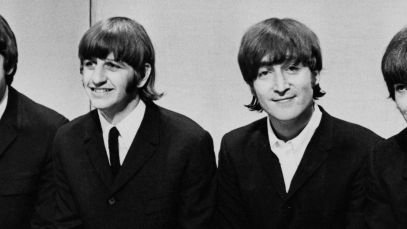 The Beatles sit together smiling