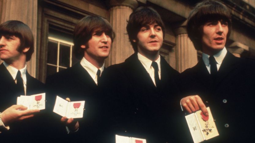 The Beatles standing together holding medals