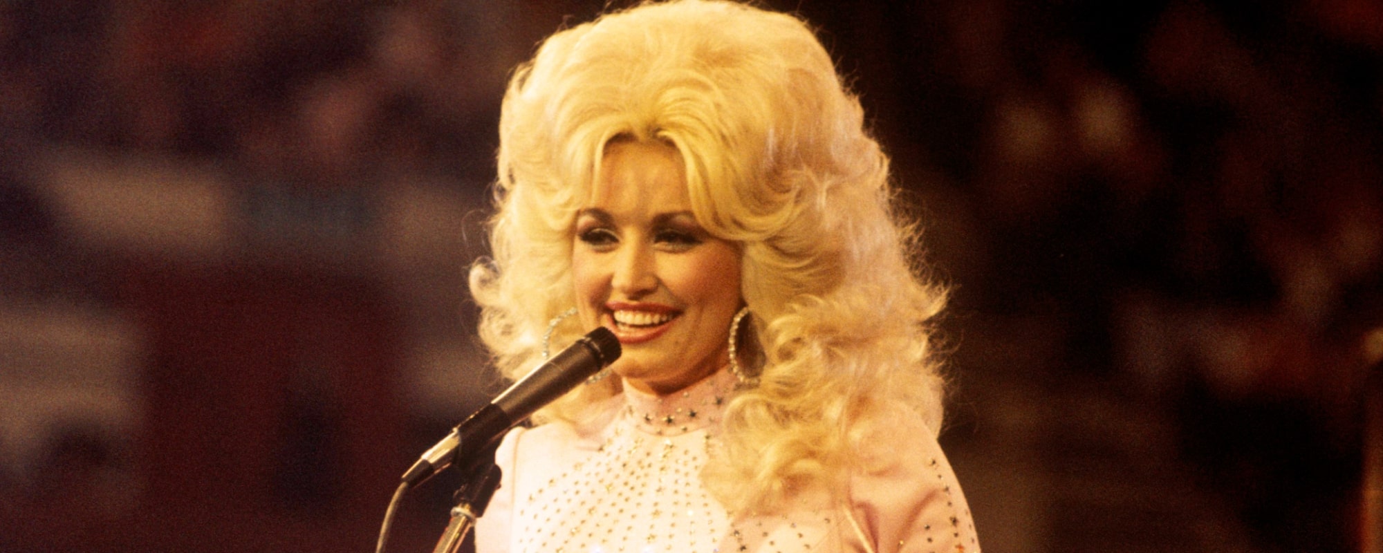 Dolly Parton, performs with a guitar, 1976.