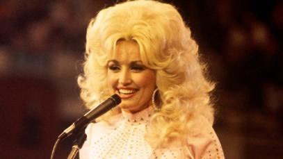 Dolly Parton, performs with a guitar, 1976.