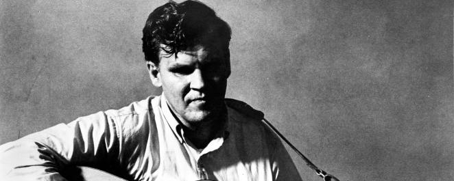 Doc Watson pose for a portrait with an acoustic guitar in circa 1968.