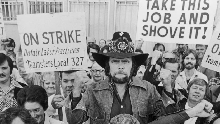Johnny Paycheck (1938 - 2003) (C) holds a teamsters union sign while joining a group of striking bookbinders, 1977.