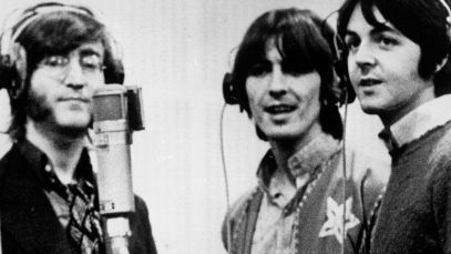 John Lennon, George Harrison, and Paul McCartney stand around microphone
