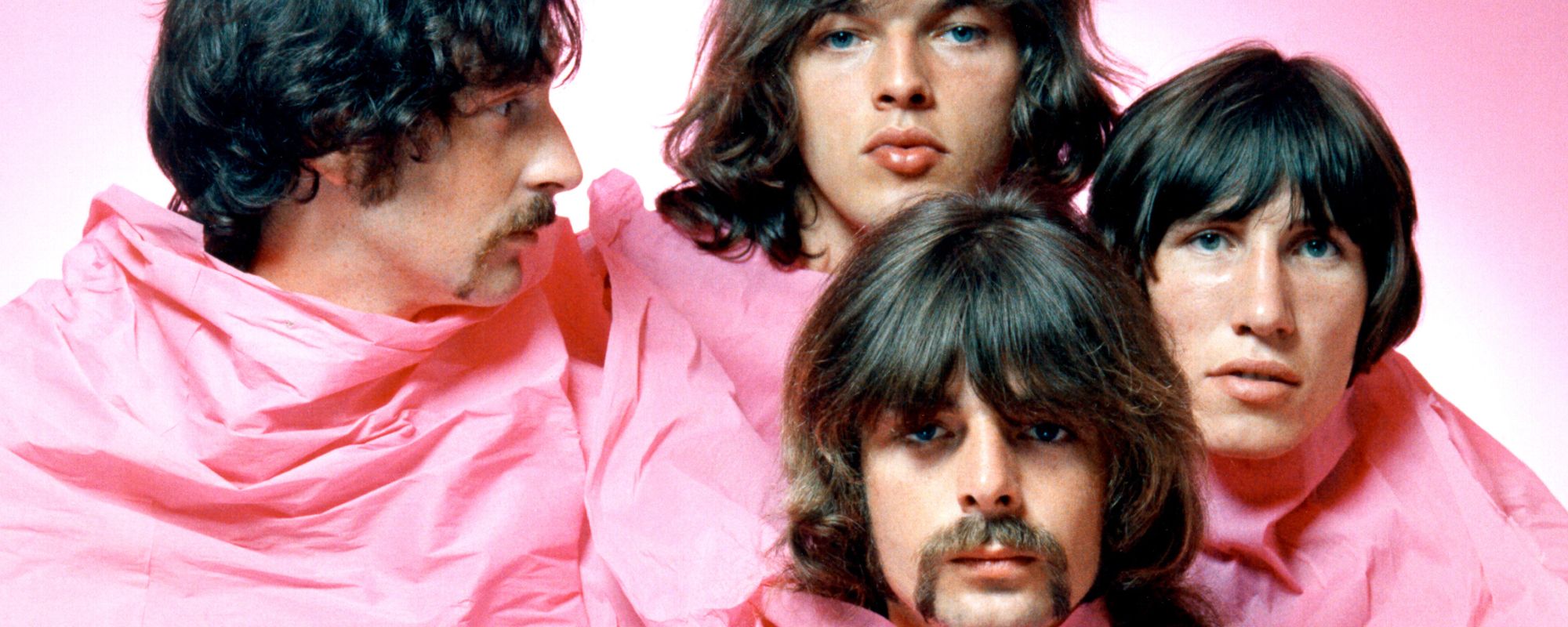 Pink Floyd poses together under pink sheet