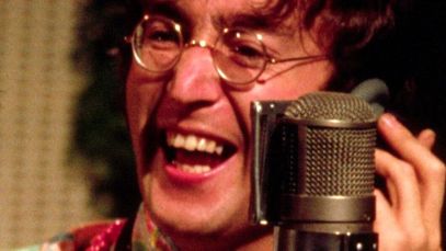 John Lennon smiling behind mic