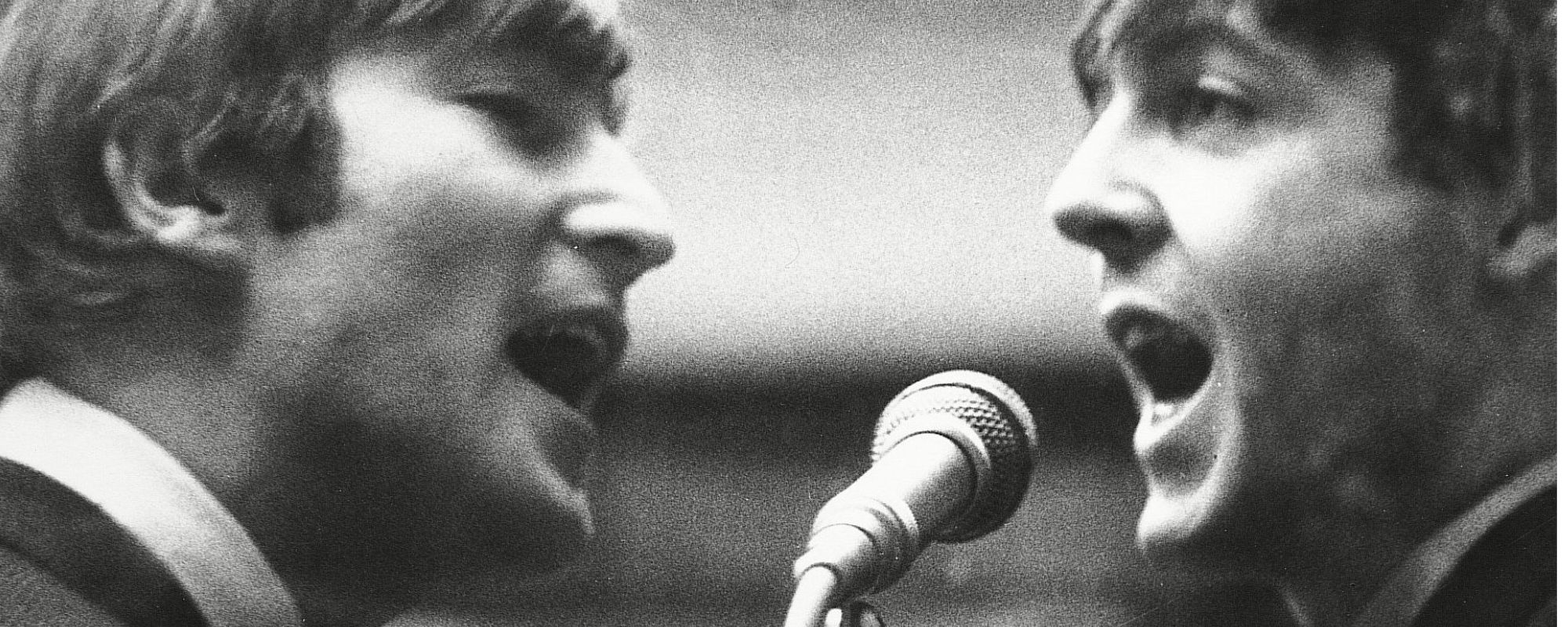 John Lennon and Paul McCartney singing into same microphone