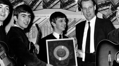 The Beatles standing with George Martin