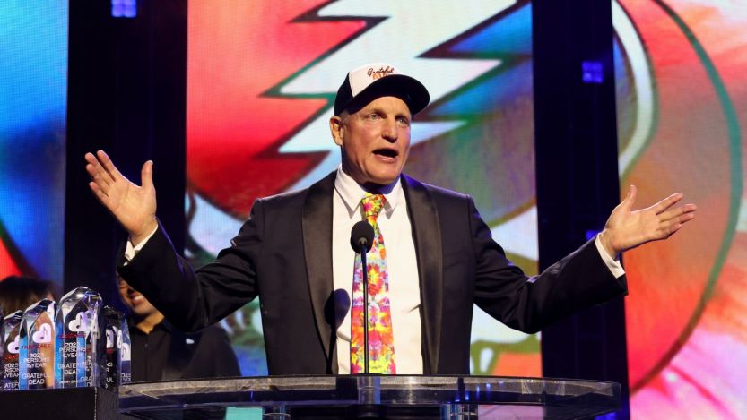 Woody Harrelson standing in front of Grateful Dead logo