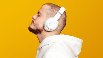 Photo of man listening to music in headphones, story about connection between dementia and hit songs