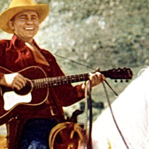Tex Ritter riding horse and playing guitar