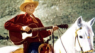 Tex Ritter riding horse and playing guitar