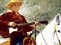 Tex Ritter riding horse and playing guitar