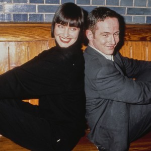 British singer and songwriter Corinne Drewery, wearing a black turtleneck sweater, and British songwriter and keyboard player Andy Connell, who wears a grey suit, of British pop group Swing Out Sister, pose back-to-back on a wooden bench against a grey brick wall, United States, circa 1987. (Photo by Vinnie Zuffante/Getty Images)