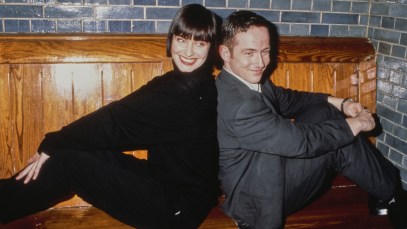 British singer and songwriter Corinne Drewery, wearing a black turtleneck sweater, and British songwriter and keyboard player Andy Connell, who wears a grey suit, of British pop group Swing Out Sister, pose back-to-back on a wooden bench against a grey brick wall, United States, circa 1987. (Photo by Vinnie Zuffante/Getty Images)