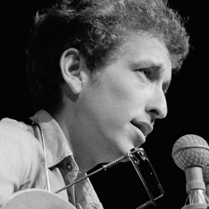 Close-up of American musician Bob Dylan as he plays acoustic guitar during a performance at the Newport Folk Festival, Newport, Rhode Island, July 1963. (Photo by Rowland Scherman/Getty Images)
