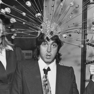 Former Beatle Paul McCartney and his wife Linda try on some of the headdresses from the off-Broadway stage show 'Sgt. Pepper's Lonely Hearts Club Band on the Road' backstage at the Beacon Theatre in New York City, 22nd December 1974. On the right is cast member Alaina Reed. (Photo by Archive Photos/Getty Images)