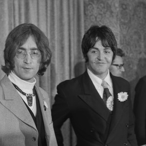 Musicians John Lennon (left) and Paul McCartney of English beat group the Beatles hold a press conference at the Americana Hotel in New York City to announce their new venture, Apple Corps, 14th May 1968. Behind Paul are producer Denis O'Dell (left) and manager Ron Kass. (Photo by Don Paulsen/Michael Ochs Archives/Getty Images)