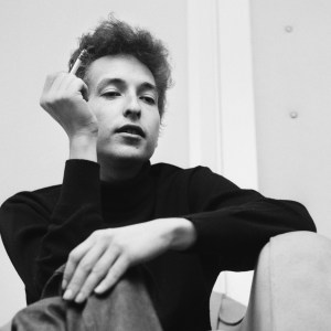 American folk singer Bob Dylan smokes a cigarette in his hotel room during his visit to London. 11th May 1964. (Photo by Daily Mirror/Daily Mirror/Mirrorpix via Getty Images)