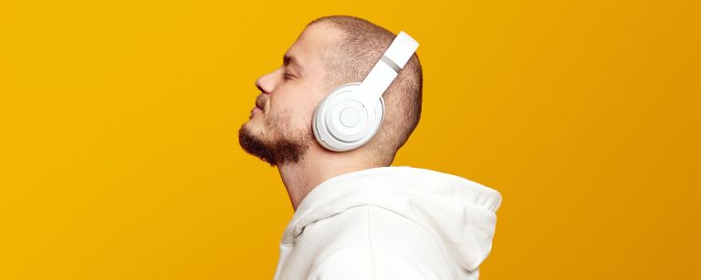 Photo of man listening to music in headphones, story about connection between dementia and hit songs